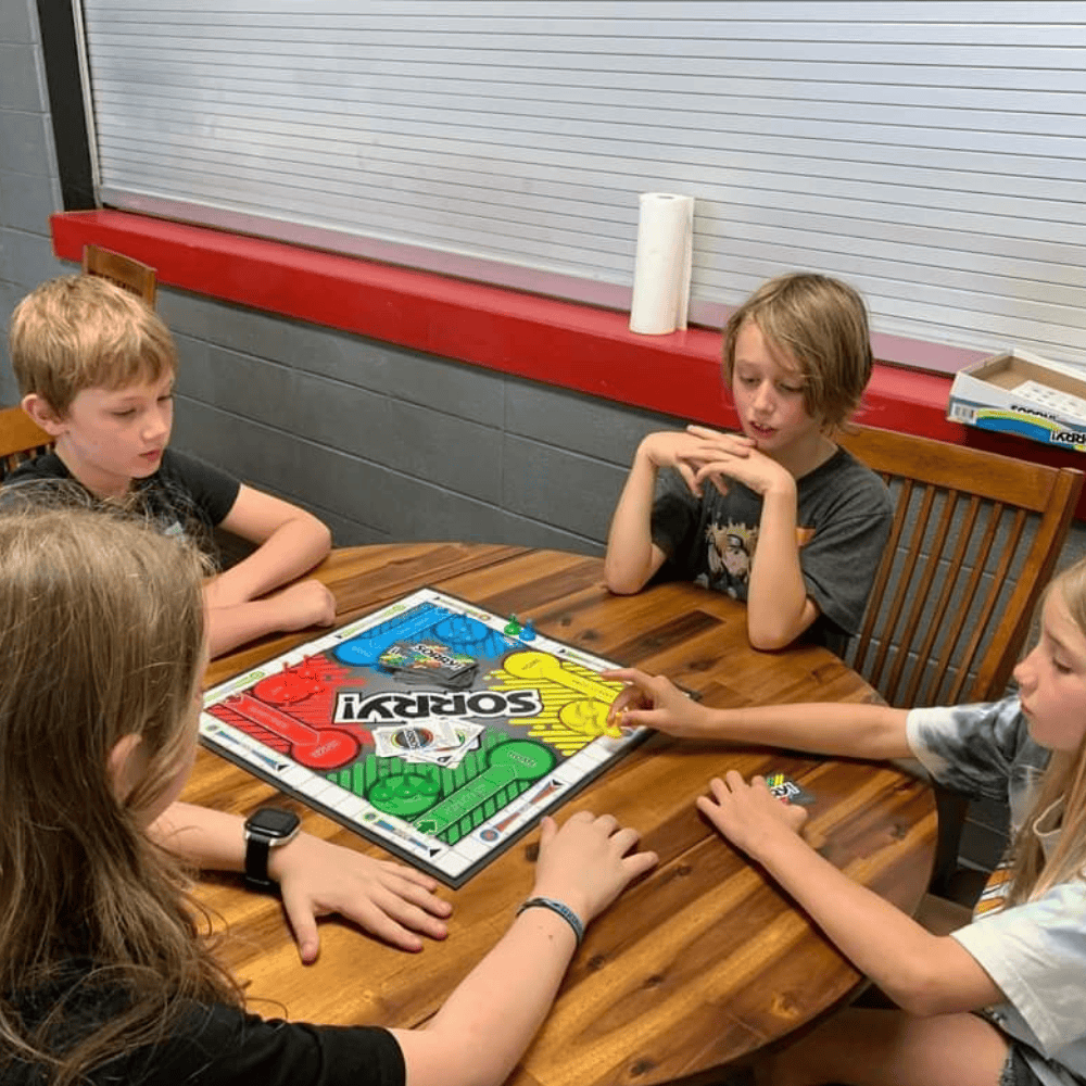 children playing a board game around a wooden table