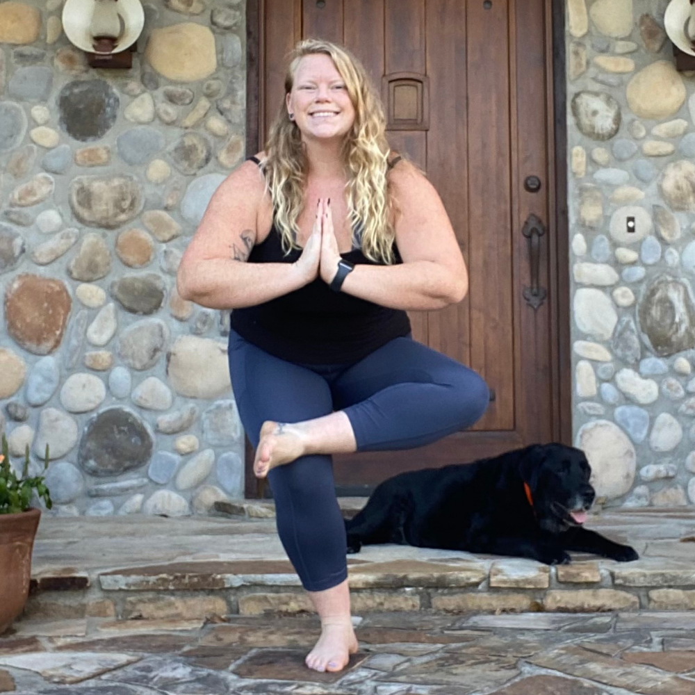 Stefani Christianson Young woman standing in front of stone building in a yoga pose